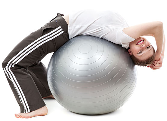 woman stretching backwards over a physical therapy ball
