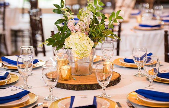 gold, blue and white table setting with bouquet in the middle of the table